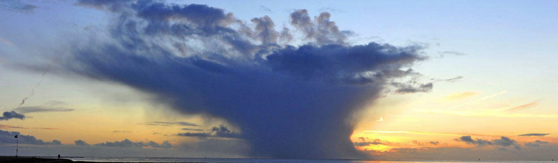 Shallow water and blue-yellow sunset sky with a dark blue cloud in the centre. © Ulrich