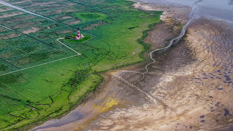 Areal picture of lighthouse set in lush green salt marhes next to exposed mudflat. Martin Stock/LKN.SH.