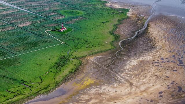 Areal picture of lighthouse set in lush green salt marhes next to exposed mudflat. Martin Stock/LKN.SH.