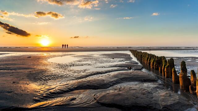 Sunset over mudflat with hiking group on the horizon. © Janis Meyer/Waddenagenda.